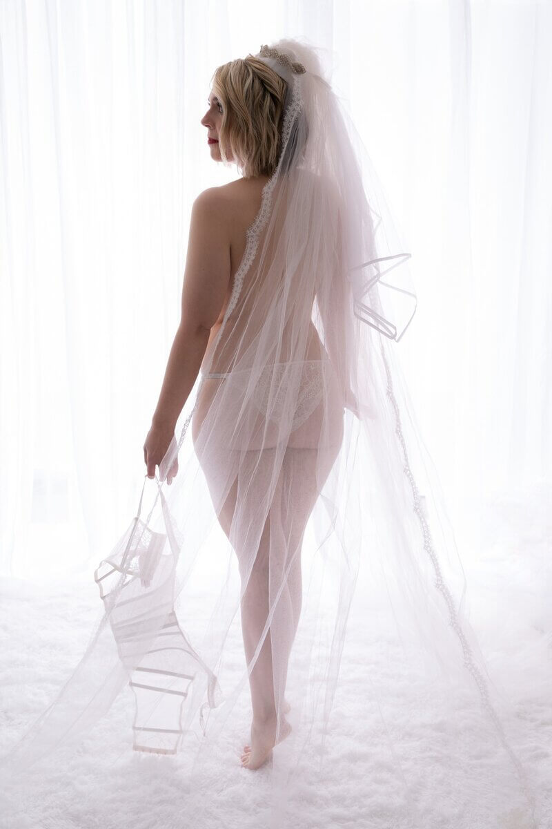 Woman facing bright window wearing bridal veil